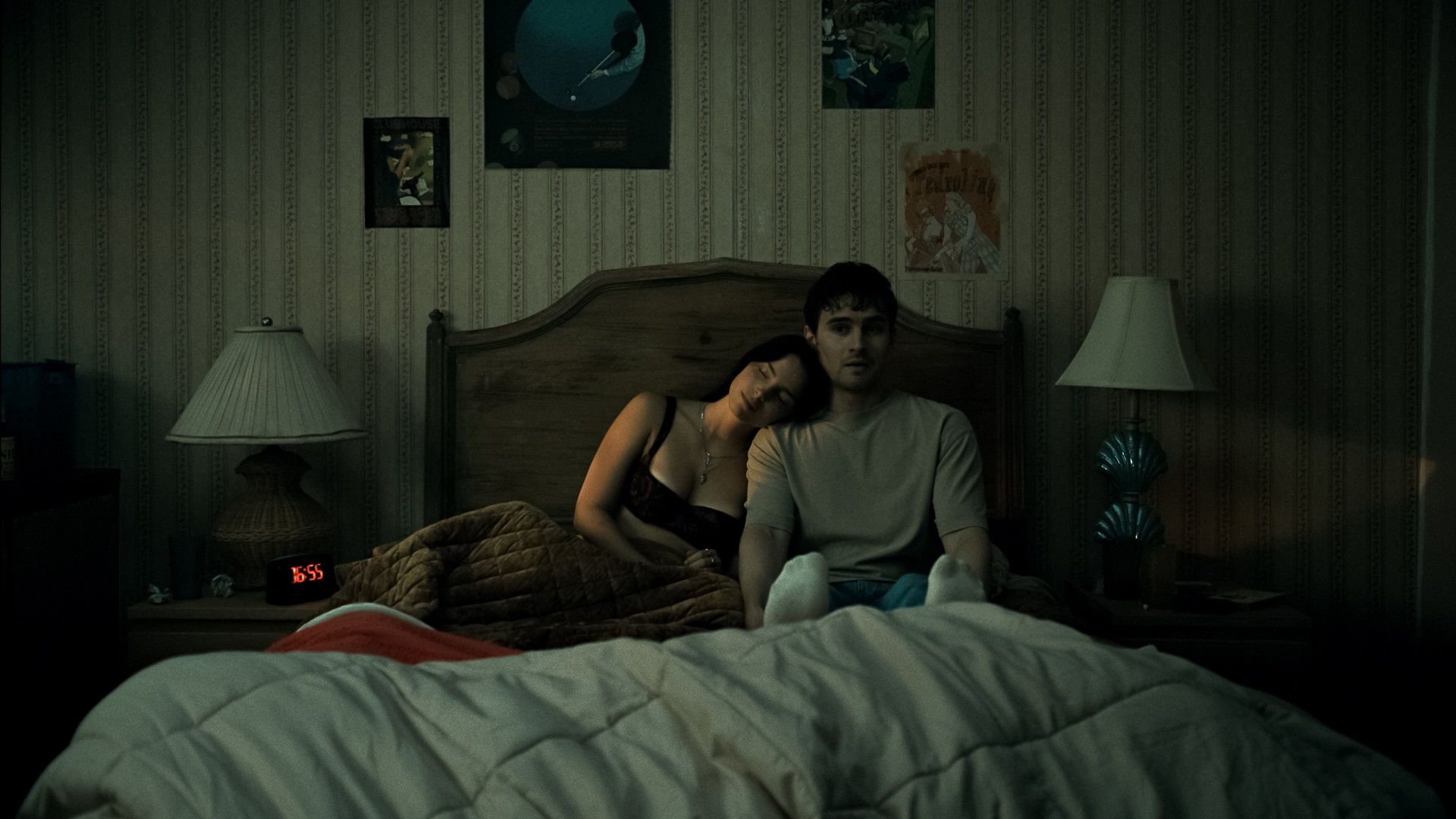 A couple sit tensely on a bed in a still from Obsession.
