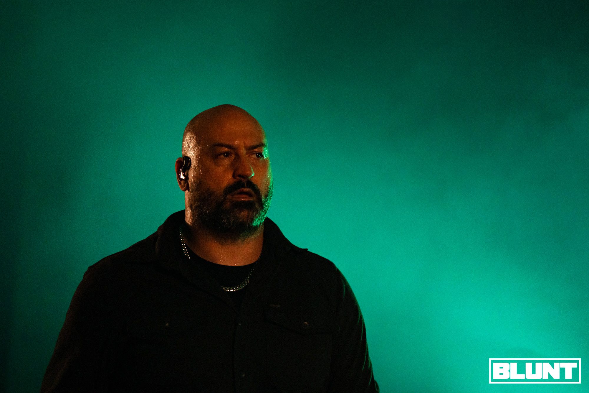 Poison The Well vocalist Jeffrey Moreira performs under green stage light.