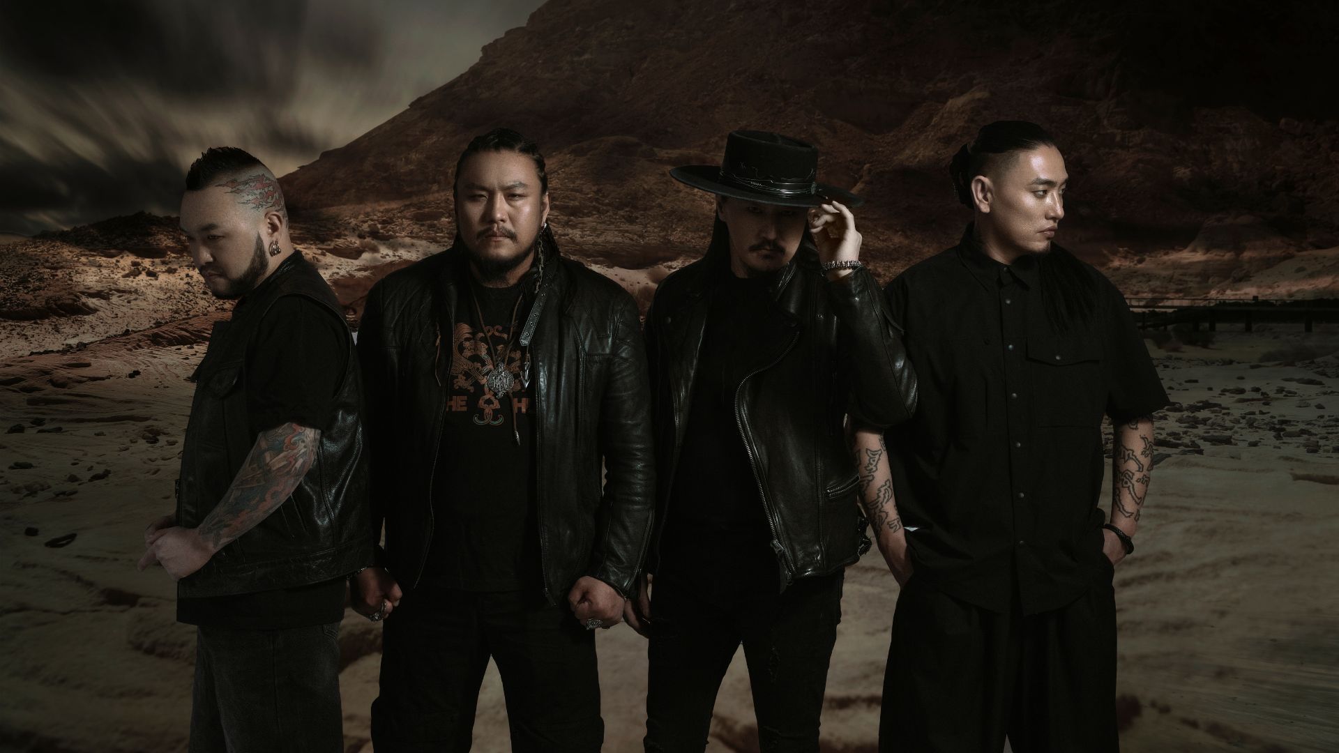 The four members of The HU stand against a rocky landscape.